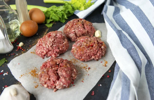 4 hambúrgueres de carne, costeletas redondas de porco com temperos em um backgr preto — Fotografia de Stock