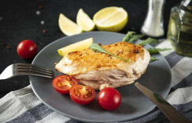 Arugula ve kiraz domatesli kızarmış tavuk filetosu, kireç, çatal, siyah arka planda bıçak.