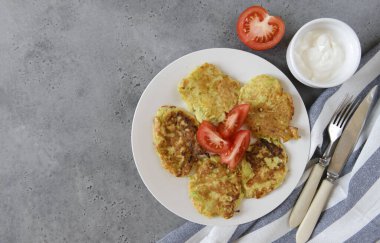 Havlunun üstünde domates ve ekşi kremalı kabaklı krep gri arka plan, çatal, bıçak,