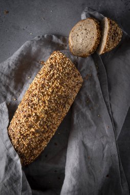 Bir somun çavdar ekmeği, gri arka planda gri peçeteyle kesilmiş parçalar, fırın, üst manzara.,