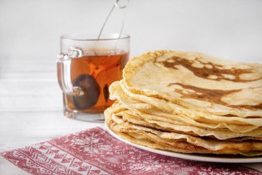 Tabakta bir yığın Rus gözlemesi, havluda bir kupa siyah çay beyaz arka planda kırmızı desenli, lezzetli bir kahvaltı.