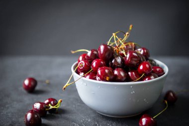 Gri arka planda olgun kırmızı kirazlar, yaz meyveleri.