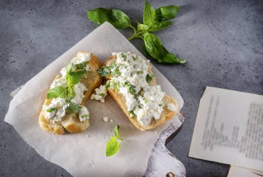 Gri arka planda yumuşak peynirli ve yeşillikli iki sandviç, Basil, kahvaltı.