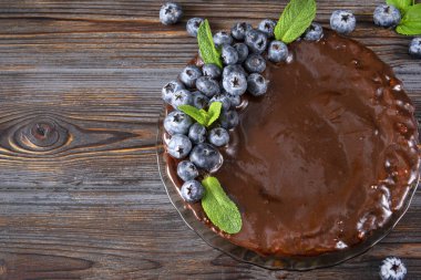 Koyu kahverengi ahşap zemin üzerinde taze yaban mersini ve nane şekerli 1 çikolatalı pasta.