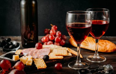 2 bardak kırmızı şarap, aperatif, şişe, peynir, kraker, jambon, reçel, üzüm, zeytin, baget.