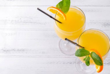 Beyaz arka planda nane ve tüpler ile taze portakal suyu bardakları, kokteyl, düz yatak, üst görünüm