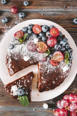 Yaban mersinli çikolatalı pasta, üzüm, nane ve pudra şekeri beyaz tabakta, bir dilim pasta, üst manzara