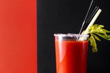Bloody Mary kokteyli, bir bardak tuzlu domates suyu, kereviz, siyah ve kırmızı arka planda tüpler.
