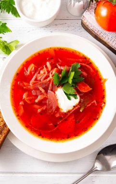 Beyaz tabakta ekşi kremalı ve maydanozlu borş, kırmızı Ukrayna sebze çorbası, üst manzara.