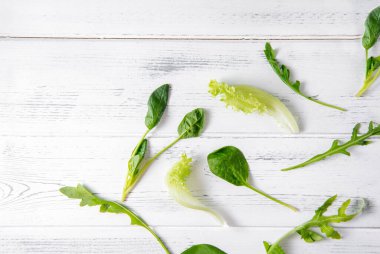 Taze yeşil marul, ıspanak, beyaz ahşap arka planda roka yaprakları, otlar., 