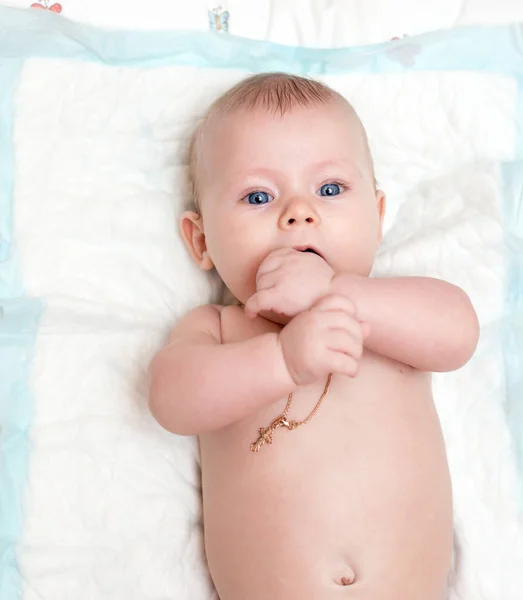 Bebé con ojos azules miente y mira a la cámara — Foto de Stock