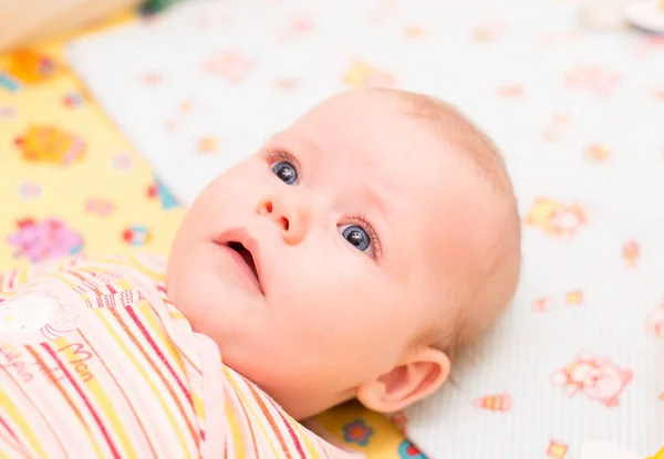 Bebê com olhos azuis mentiras e olhar para a câmera — Fotografia de Stock