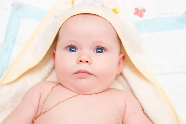 Bebé con ojos azules miente y mira a la cámara — Foto de Stock