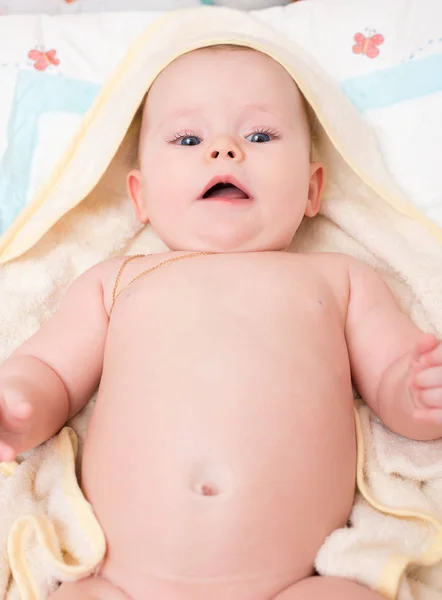 Bebé con ojos azules miente y mira a la cámara — Foto de Stock