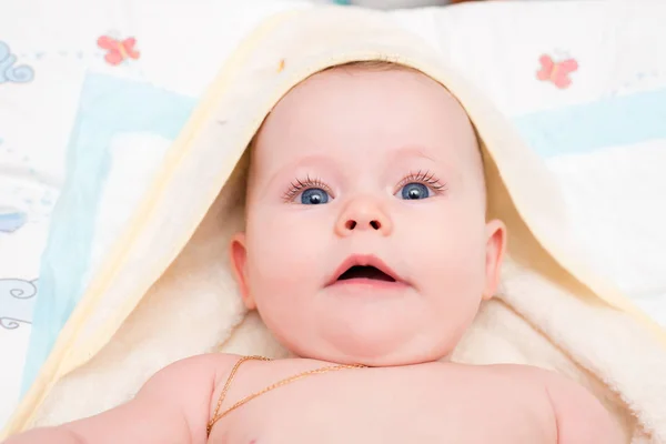 Bebé con ojos azules miente y mira a la cámara — Foto de Stock