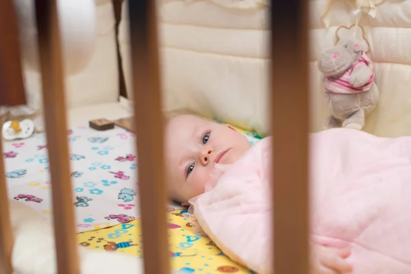 Leuke baby liggend op zijn buik in zijn bed. — Stockfoto