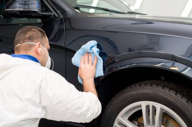 Oto yıkama makinesiyle araba cilalayan bir adam.