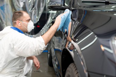 Oto yıkama makinesiyle araba cilalayan bir adam.