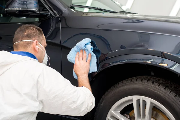 Oto yıkama makinesiyle araba cilalayan bir adam.