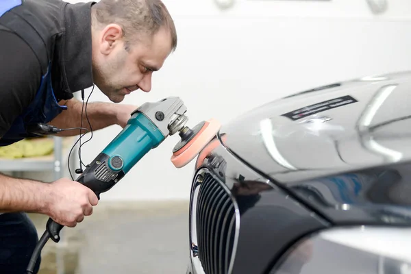 Oto yıkama makinesiyle araba cilalayan bir adam.