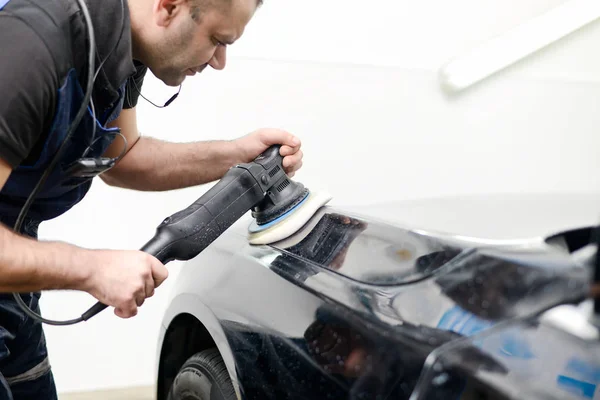 Homem em um carro lavar polimento carro com uma máquina de polir — Fotografia de Stock