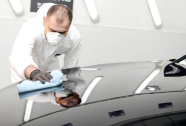 Oto yıkama makinesiyle araba cilalayan bir adam.