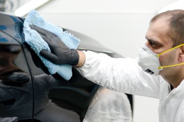 Oto yıkama makinesiyle araba cilalayan bir adam.