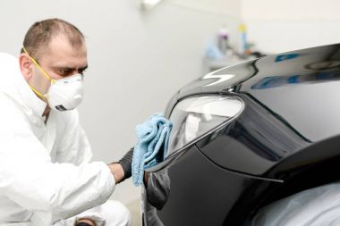 Oto yıkama makinesiyle araba cilalayan bir adam.