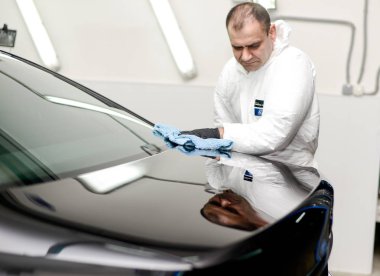 Oto yıkama makinesiyle araba cilalayan bir adam.