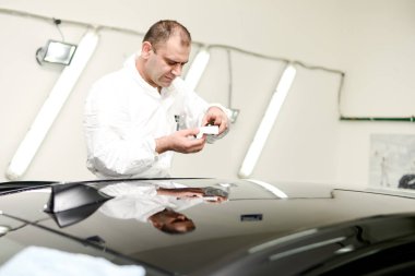 Oto yıkama makinesiyle araba cilalayan bir adam.