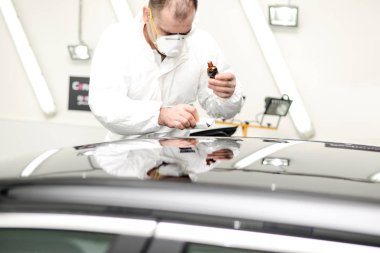 Oto yıkama makinesiyle araba cilalayan bir adam.