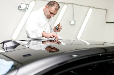 Oto yıkama makinesiyle araba cilalayan bir adam.