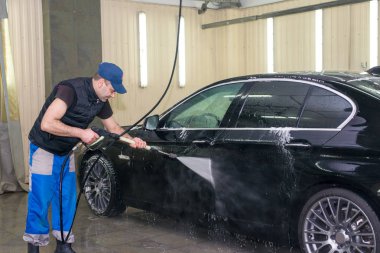 Bir adam köpük ile siyah bir araba yıkar