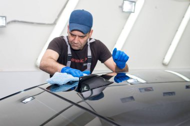 Bir adam siyah bir araba parlatır