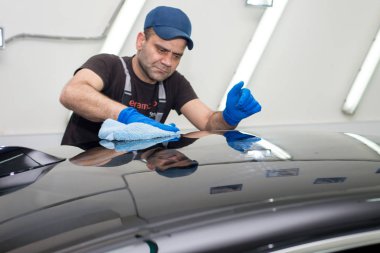 Bir adam siyah bir araba parlatır