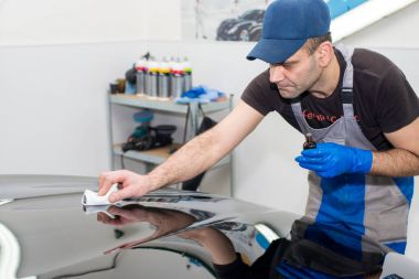 Bir adam siyah bir araba parlatır