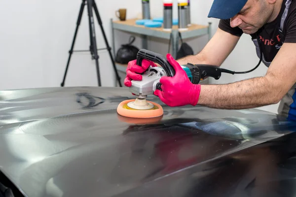 Een Man Polijst Een Zwarte Auto Met Een Polijst Machine — Stockfoto