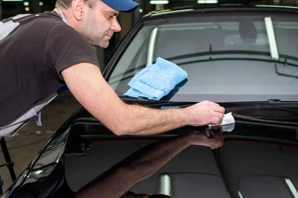 Un hombre pule un coche negro — Foto de Stock