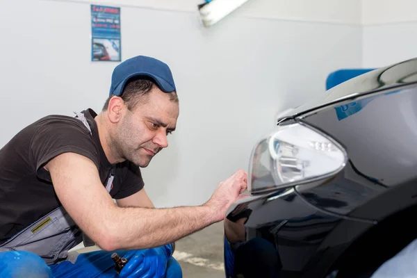 Un hombre pule un coche negro — Foto de Stock