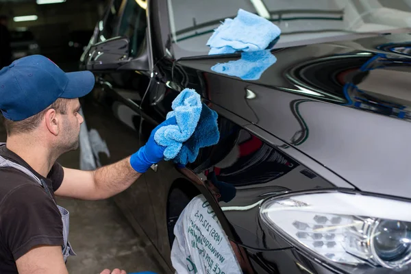 Bir adam siyah bir araba parlatır