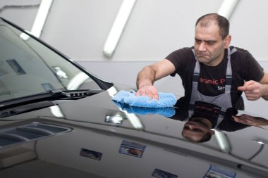 Bir adam siyah bir araba parlatır