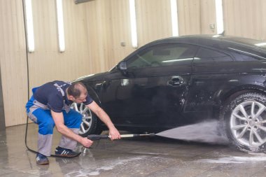 Bir adam köpük ile siyah bir araba yıkar