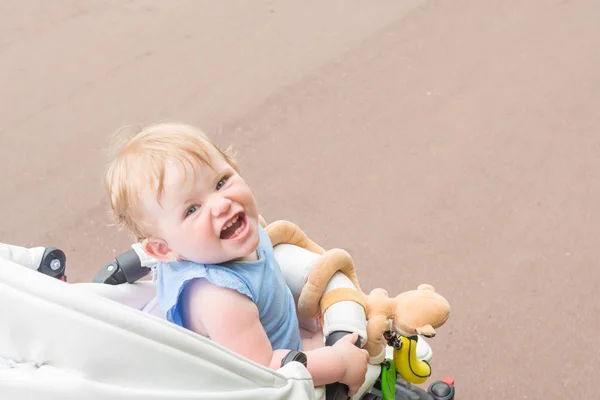 Ребенок сидит в коляске и сладко улыбается — стоковое фото