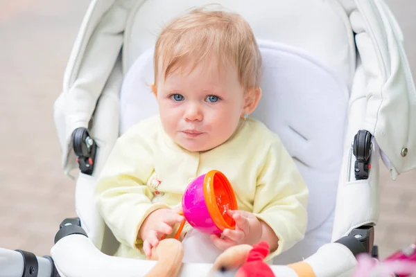 Uma criança bebê está sentada em um carrinho — Fotografia de Stock