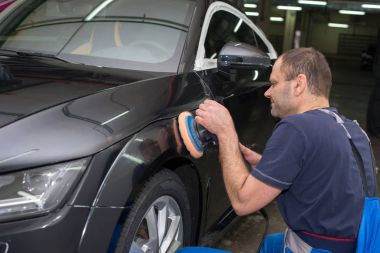 Bir adam siyah bir araba parlatır