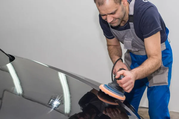 Un hombre pule un coche negro — Foto de Stock