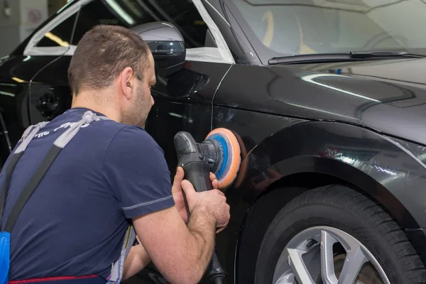 Bir adam siyah bir araba parlatır