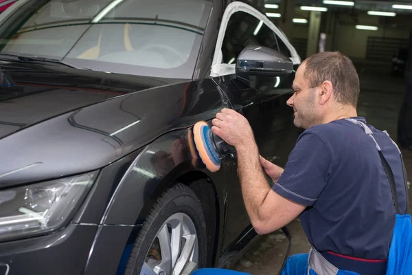 Bir adam siyah bir araba parlatır