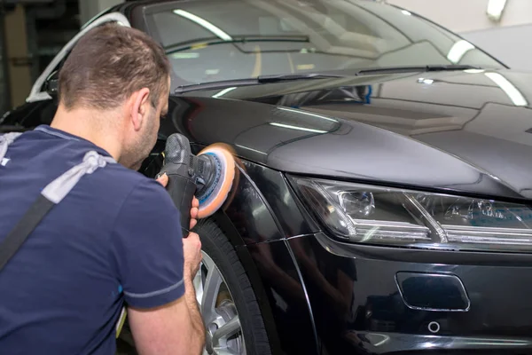 Bir adam siyah bir araba parlatır