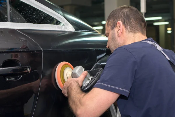 A man polishes a black car — Stock Photo, Image